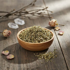 Coupelle en bois remplie de fumeterre séchée vert gris en copeaux sur table en bois avec cristaux et roses séchées.