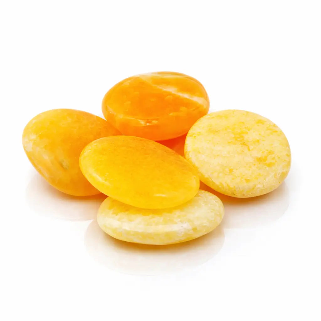 Tas de cinq galets arrondis en calcite orange aux nuances allant du jaune pâle au mandarine, sur fond blanc.
