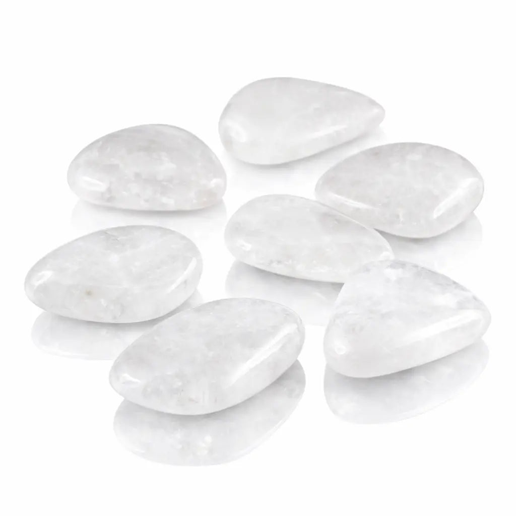 Sept galets polis de quartz blanc laiteux, de forme ovale et triangulaire, sur fond blanc réfléchissant.