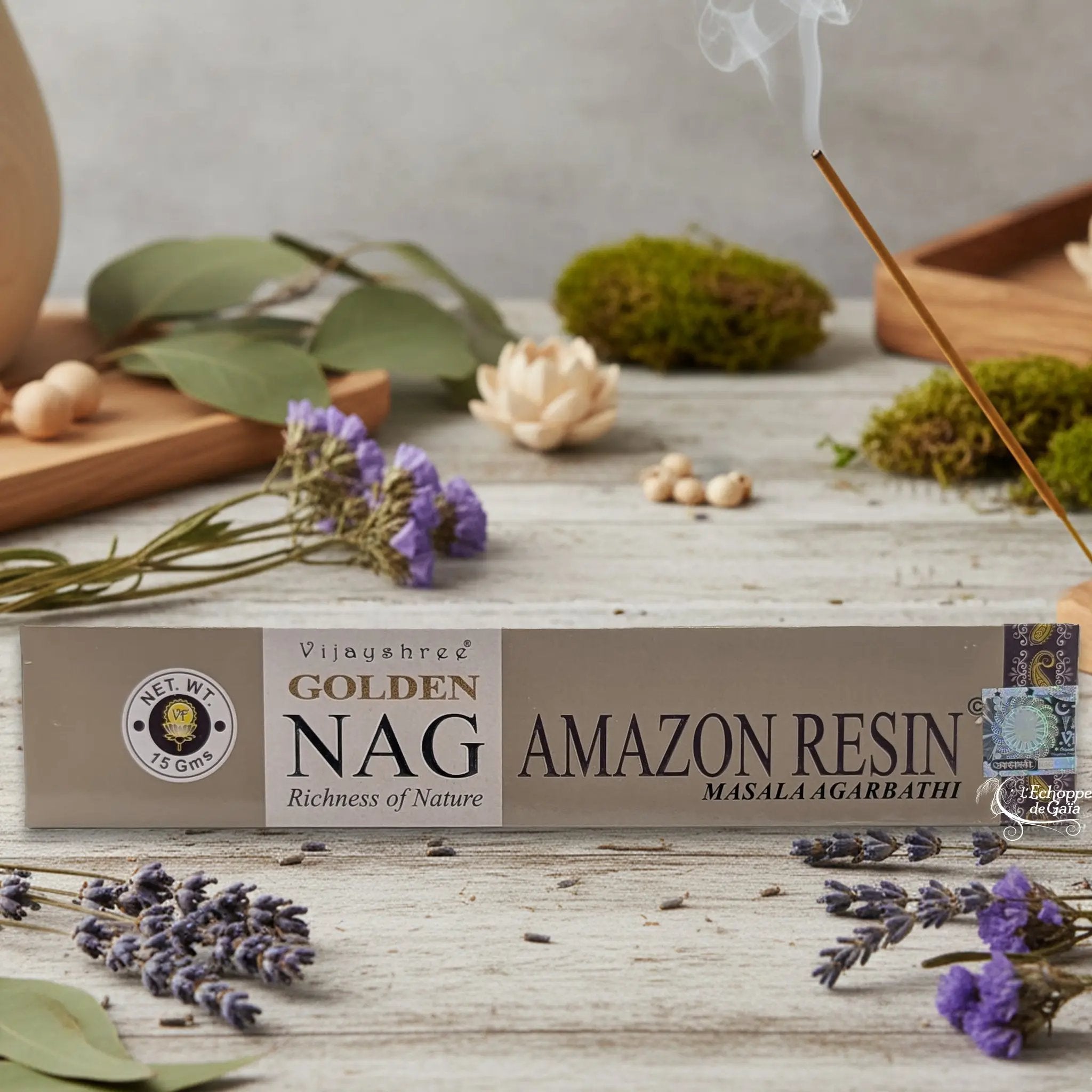 Boîte d'encens Vijayshree Golden Nag "Amazon Resin" Masala Agarbathi, posée sur une table avec de la lavande et un bâton d'encens fumant.