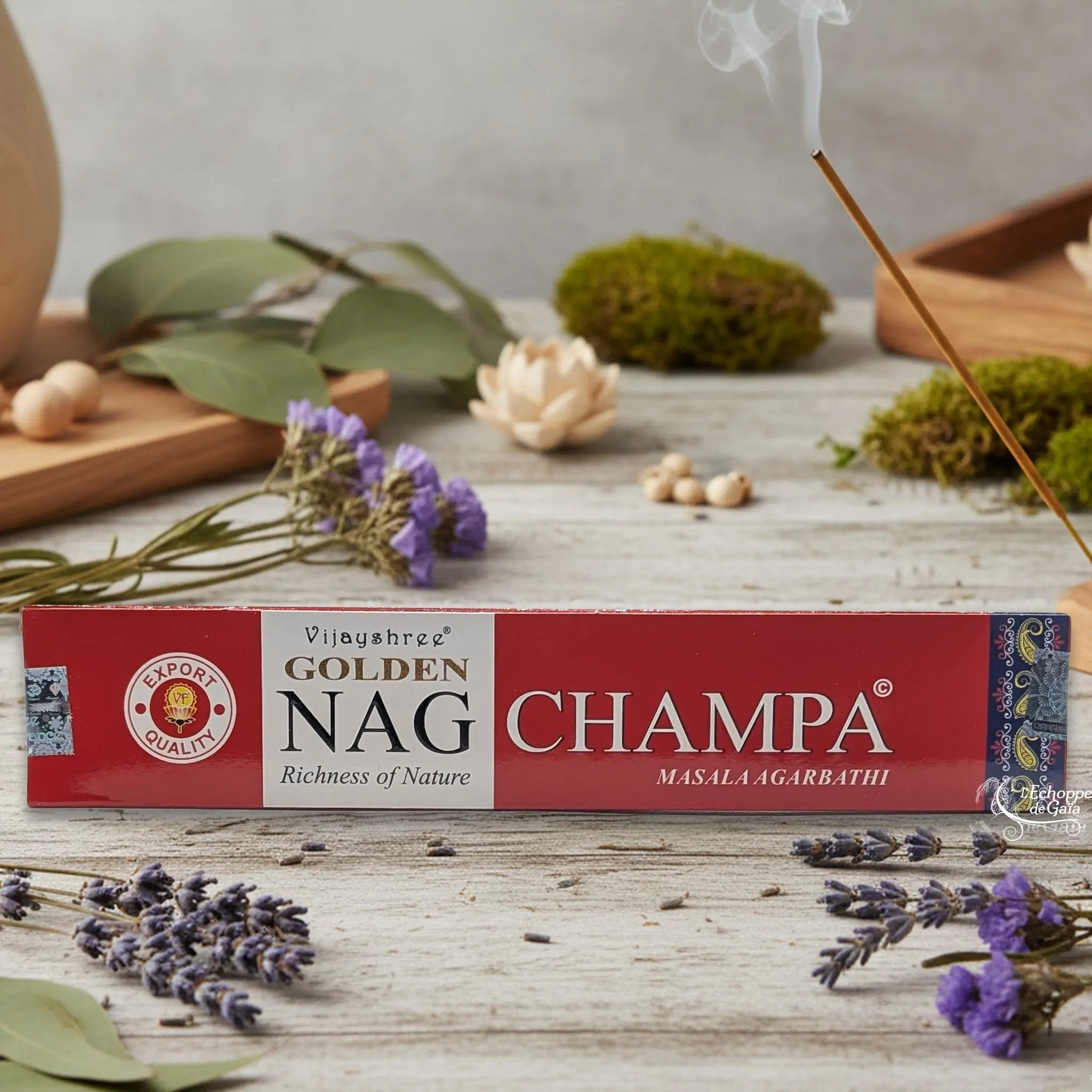 Boîte d'encens Vijayshree Golden Nag "Champa" Masala Agarbathi, posée sur une table avec de la lavande et un bâton d'encens fumant.