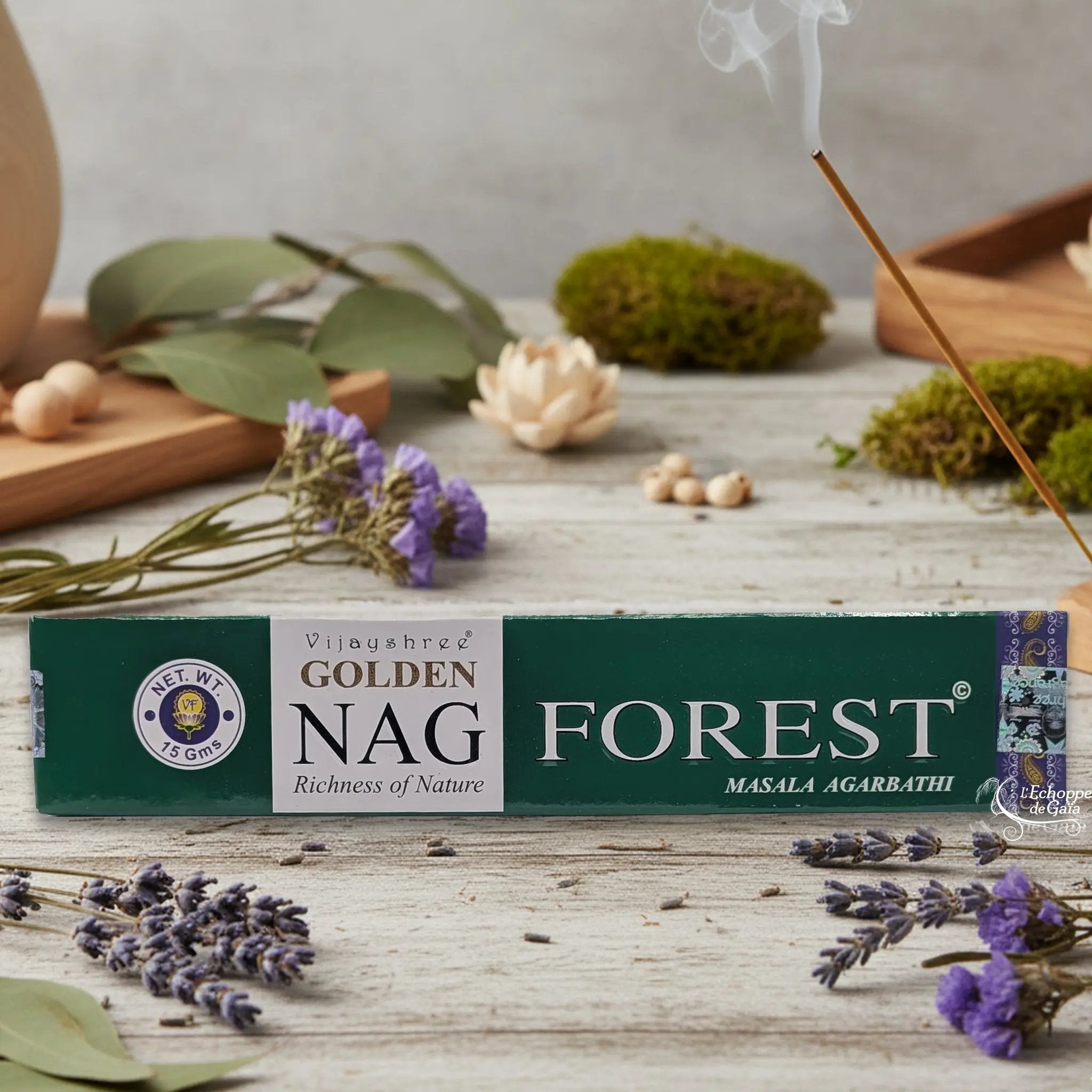 Boîte d'encens Vijayshree Golden Nag "Forest" Masala Agarbathi, posée sur une table avec de la lavande et un bâton d'encens fumant.