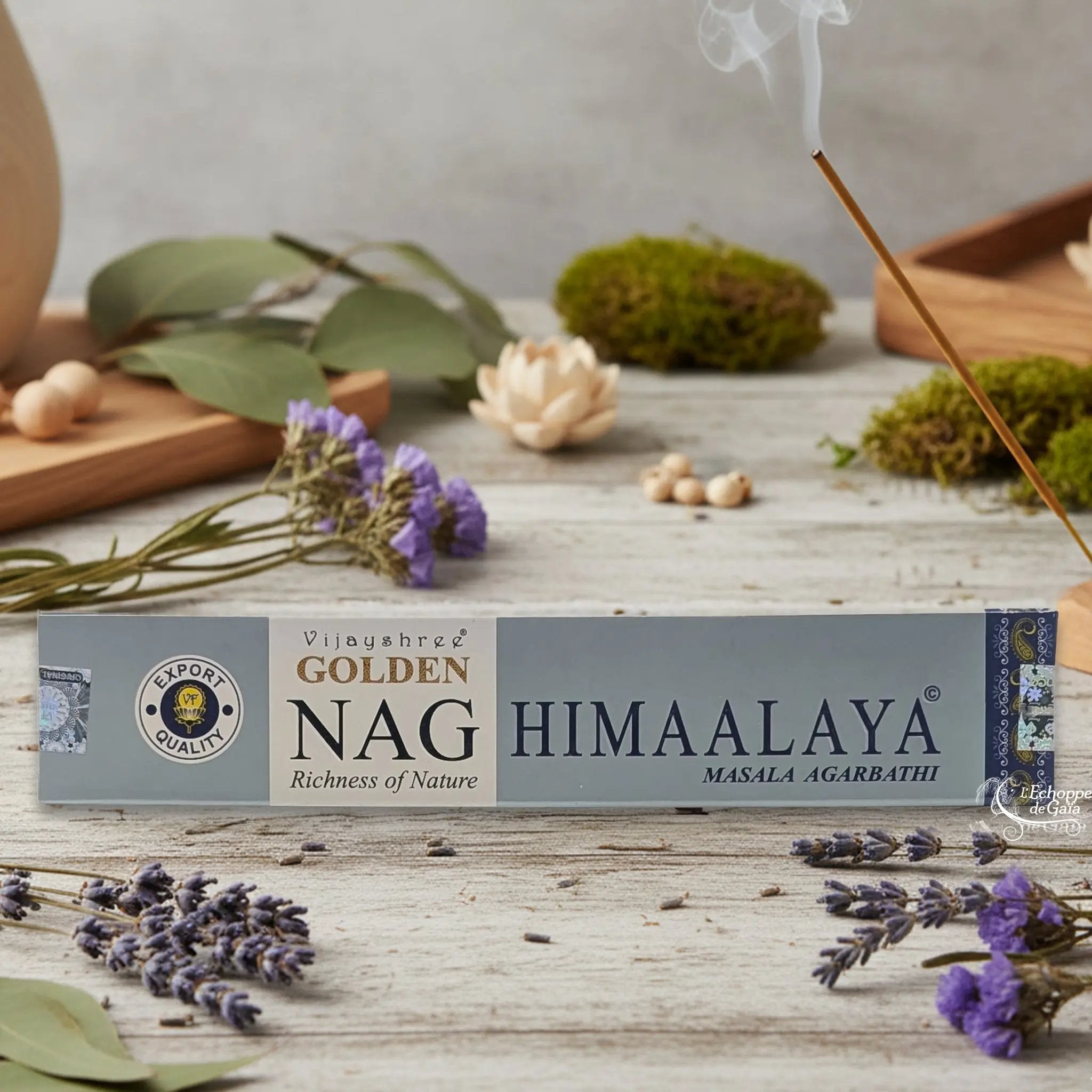 Boîte d'encens Vijayshree Golden Nag "Himaalaya" Masala Agarbathi, posée sur une table avec de la lavande et un bâton d'encens fumant.