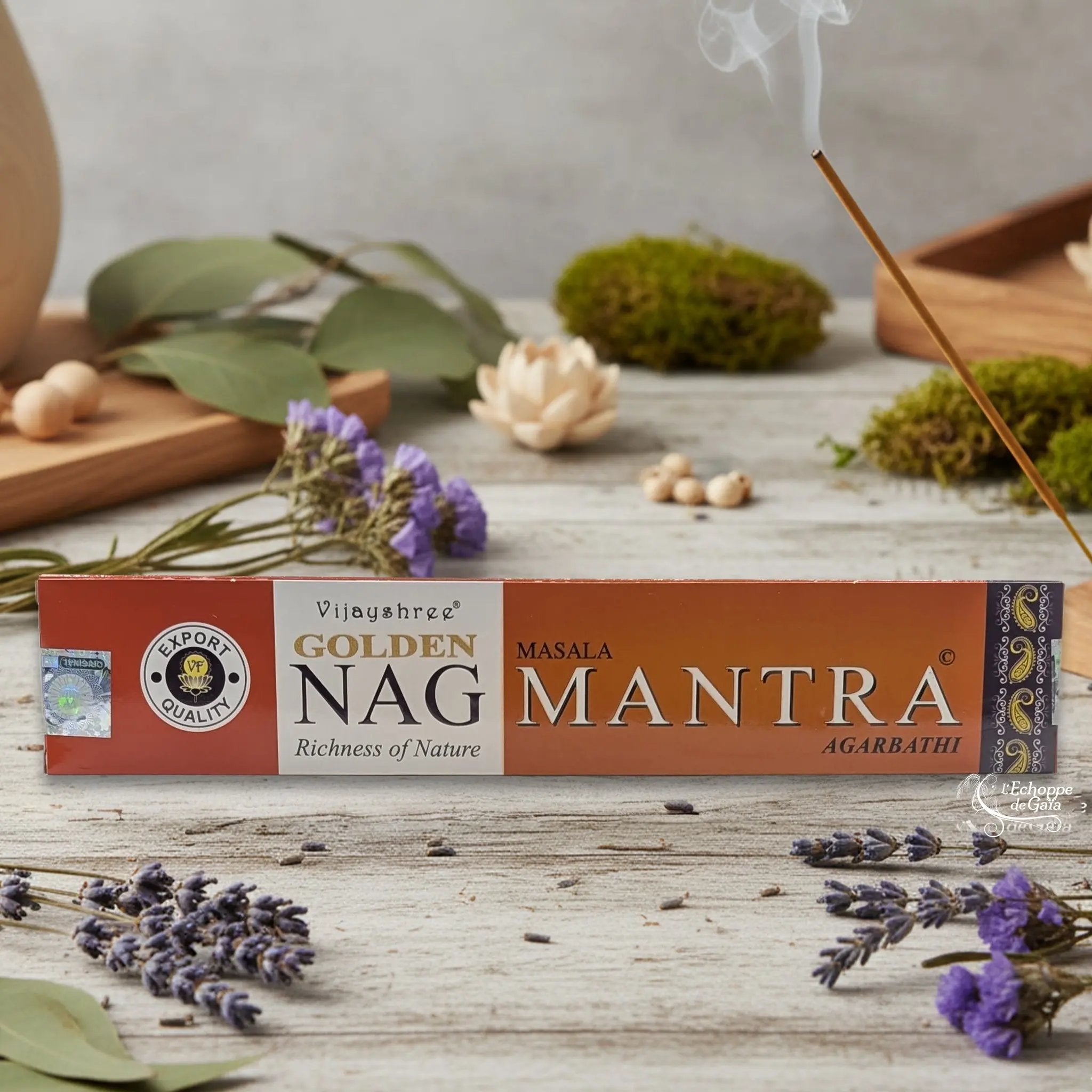 Boîte d'encens Vijayshree Golden Nag "Mantra" Masala Agarbathi, posée sur une table avec de la lavande et un bâton d'encens fumant.