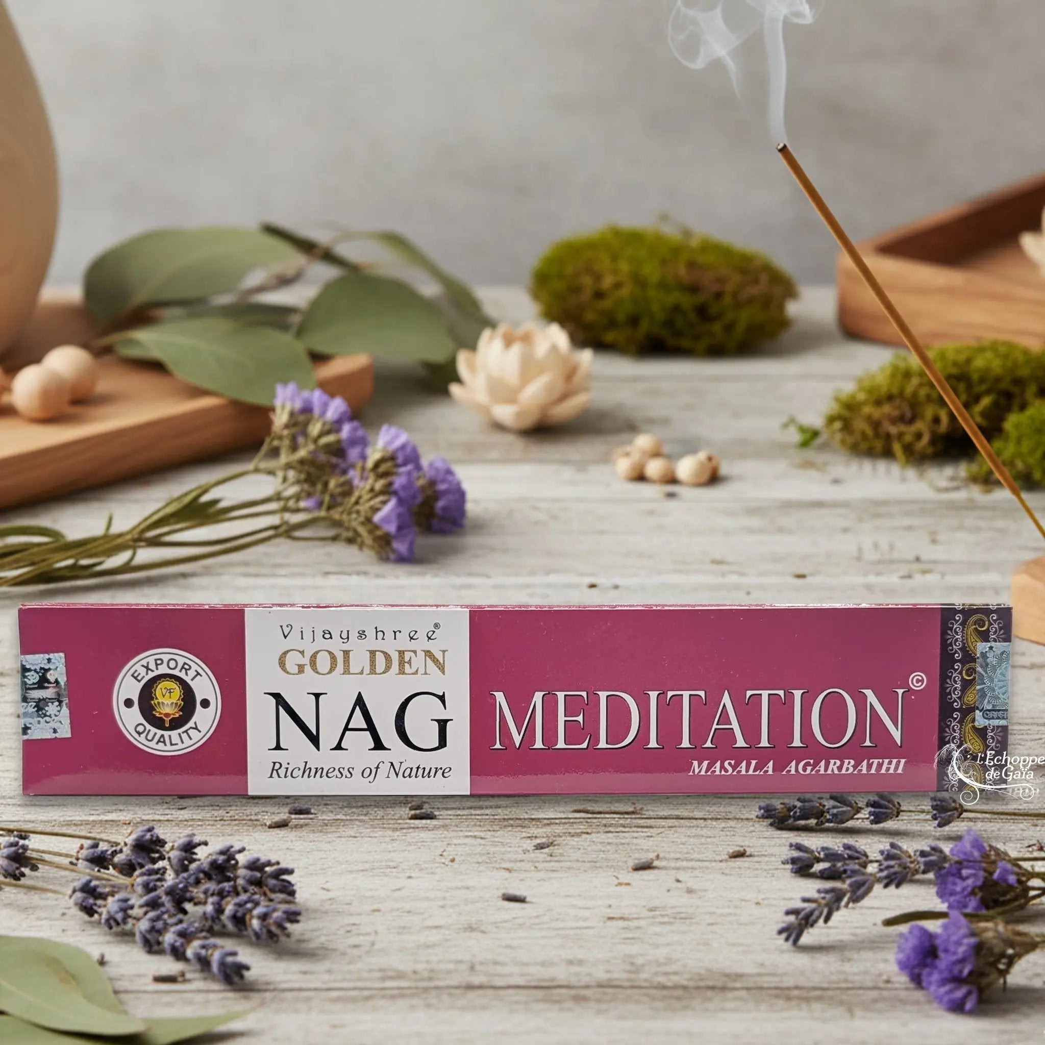 Boîte d'encens Vijayshree Golden Nag "Meditation" Masala Agarbathi, posée sur une table avec de la lavande et un bâton d'encens fumant.