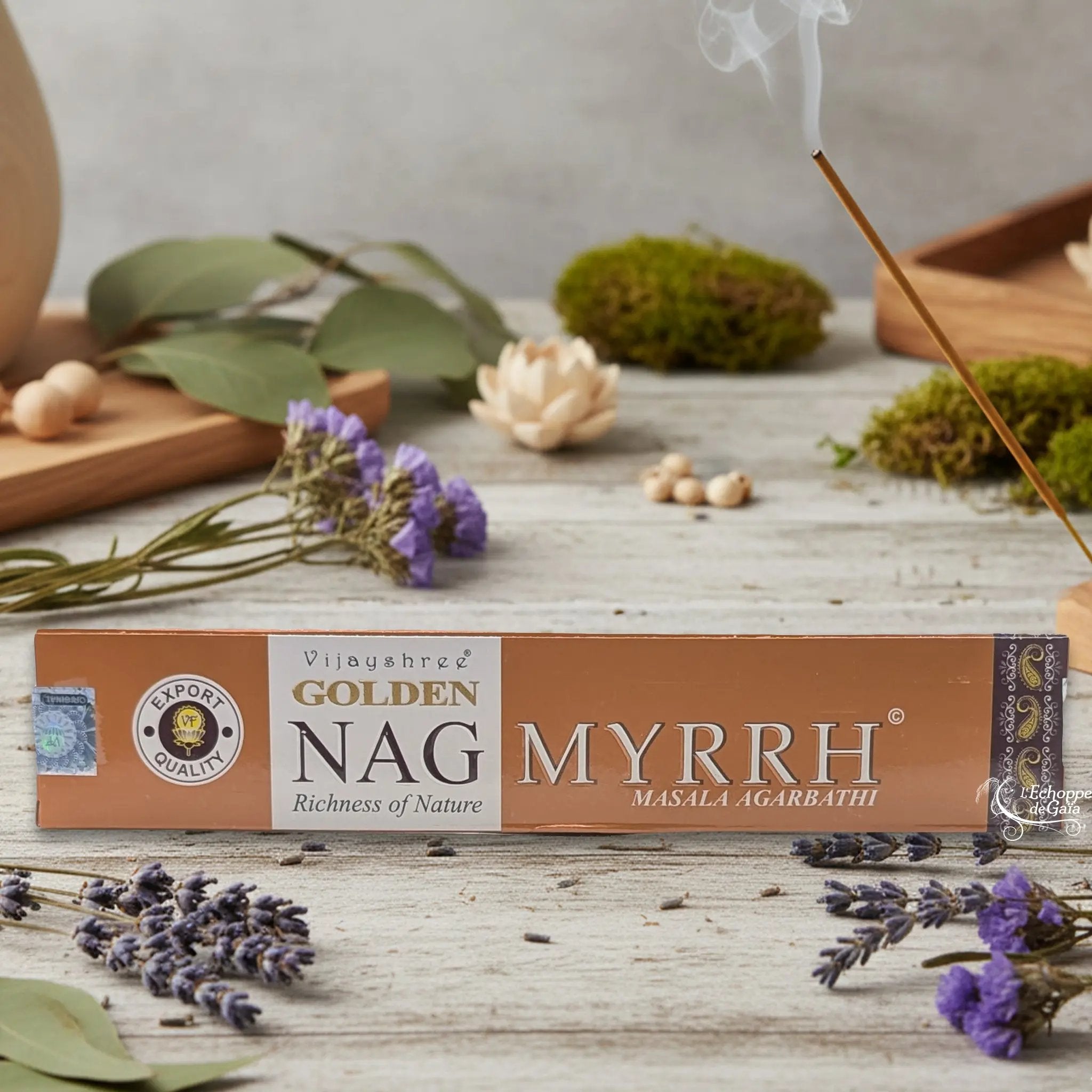 Boîte d'encens Vijayshree Golden Nag "Myrrh" Masala Agarbathi, posée sur une table avec de la lavande et un bâton d'encens fumant.