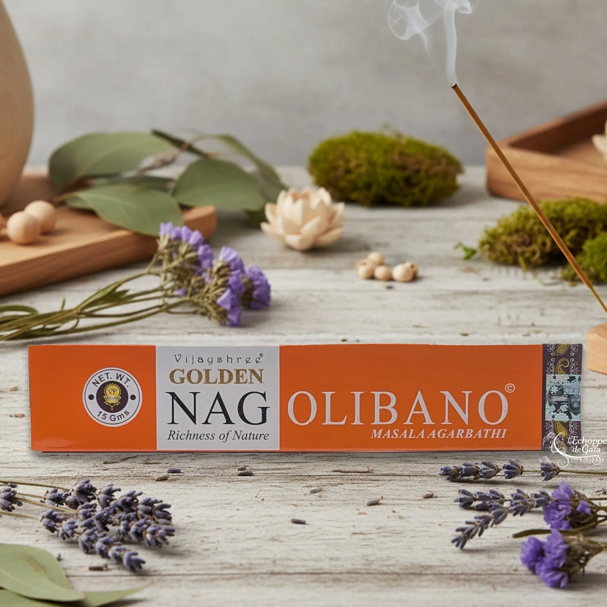 Boîte d'encens Vijayshree Golden Nag "Olibano" Masala Agarbathi, posée sur une table avec de la lavande et un bâton d'encens fumant.