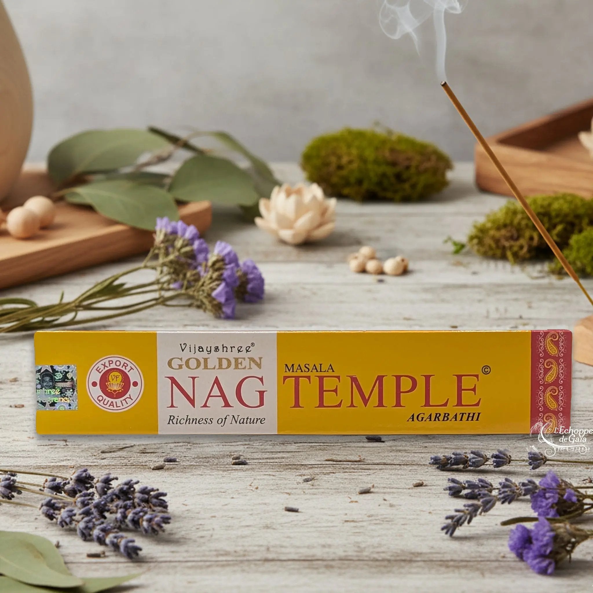 Boîte d'encens Vijayshree Golden Nag "Temple" Masala Agarbathi, posée sur une table avec de la lavande et un bâton d'encens fumant.