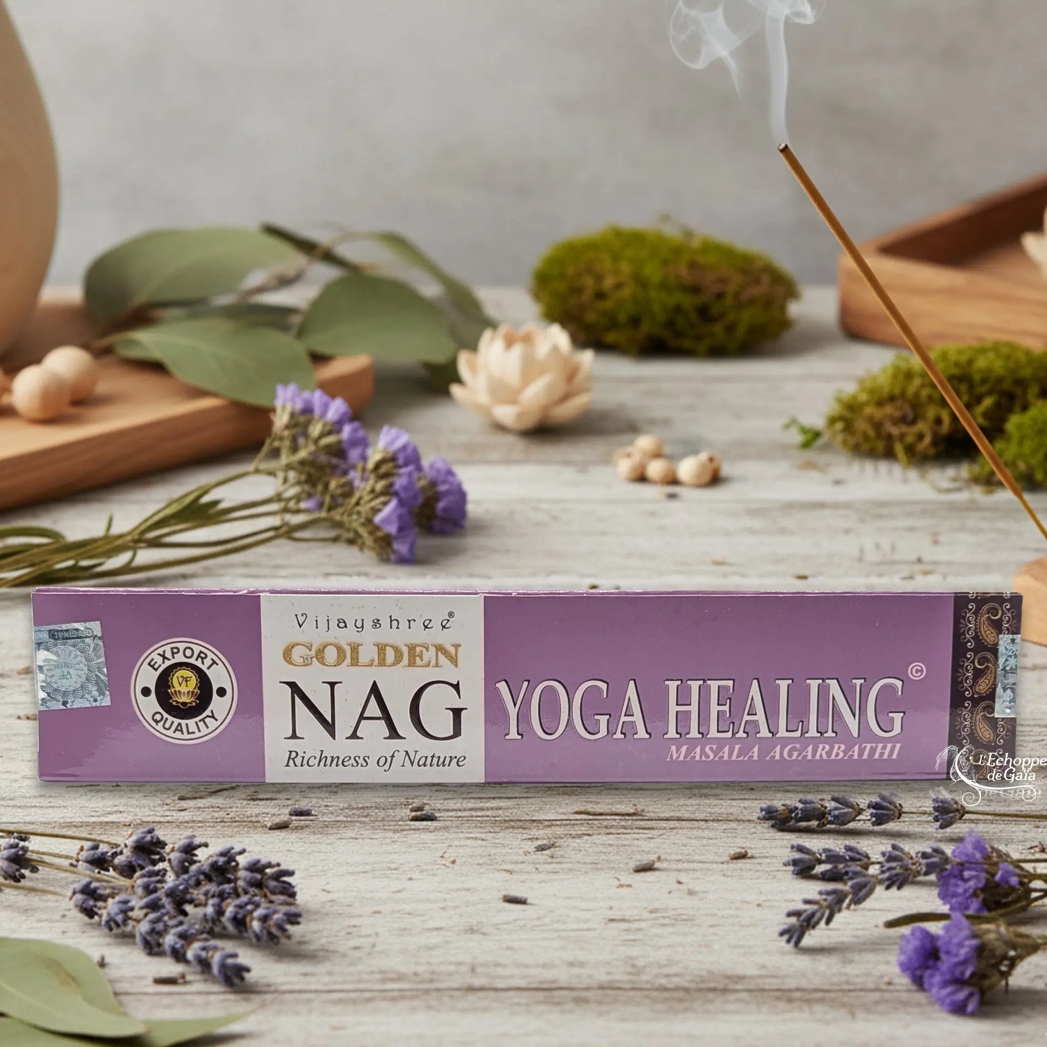Boîte d'encens Vijayshree Golden Nag "Yoga Healing" Masala Agarbathi, posée sur une table avec de la lavande et un bâton d'encens fumant.