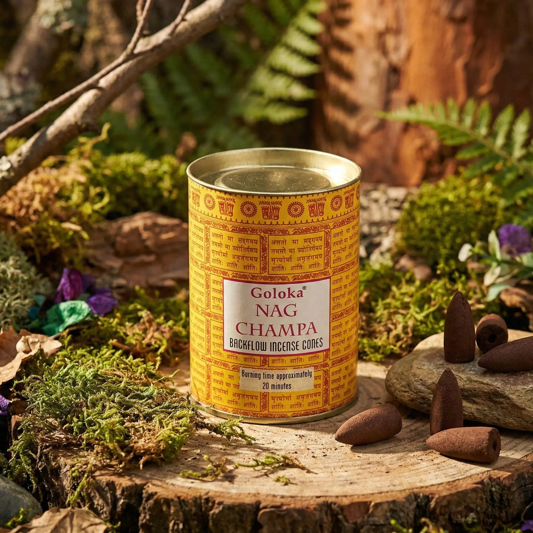 Boîte cylindrique Goloka Nag Champa pour cônes backflow, emballage jaune à écritures, couvercle doré, cônes d’encens bruns au premier plan.