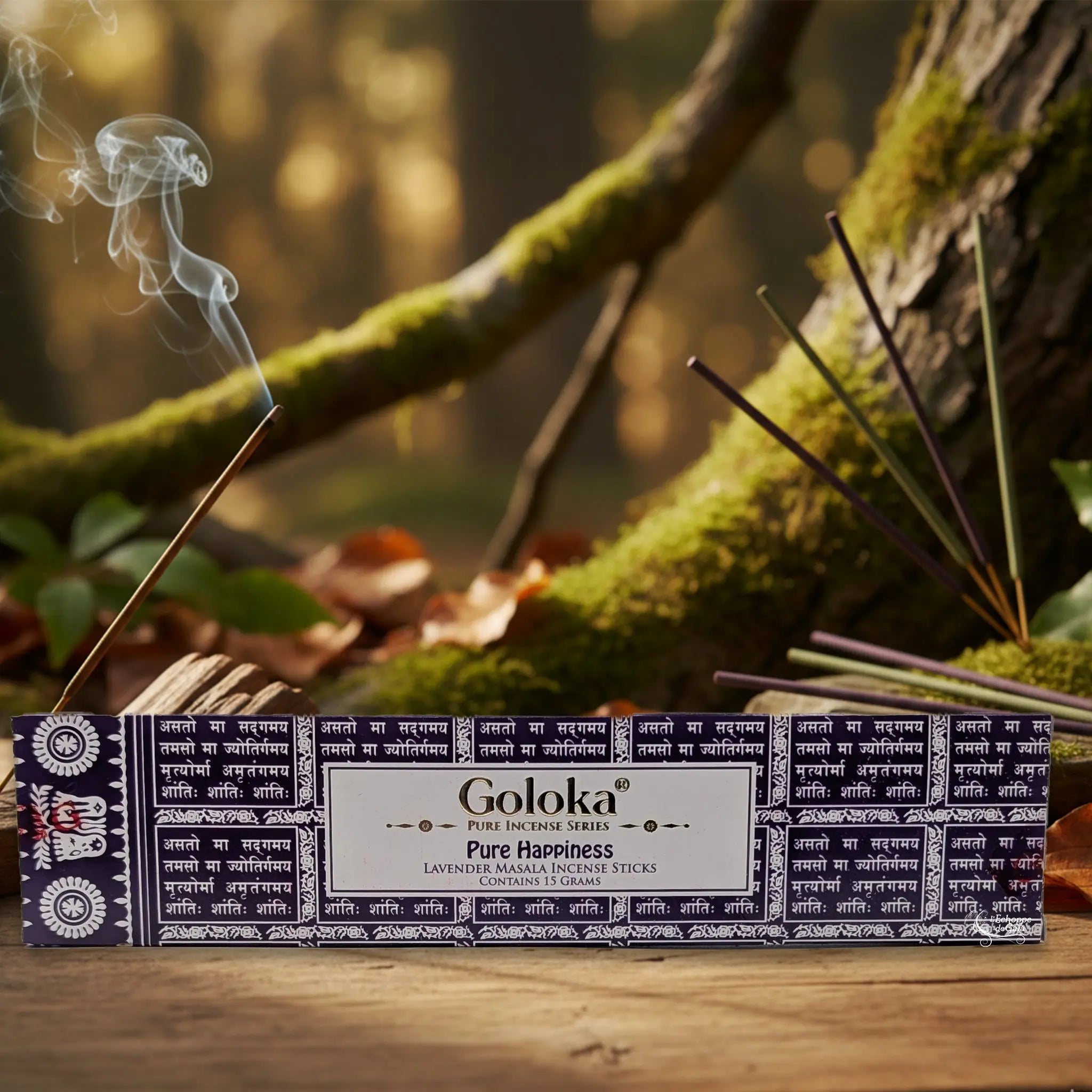Boîte d’encens Goloka « Pure Happiness » (lavender) posée sur une table en bois, avec un bâtonnet allumé et de la fumée, sur fond de forêt moussue.