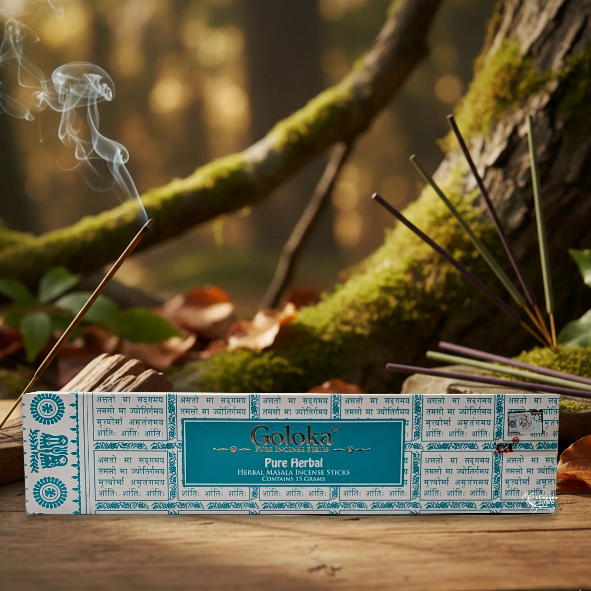 Boîte d’encens Goloka « Pure Herbal » posée sur une table en bois, avec un bâtonnet allumé et de la fumée, sur fond de forêt moussue.