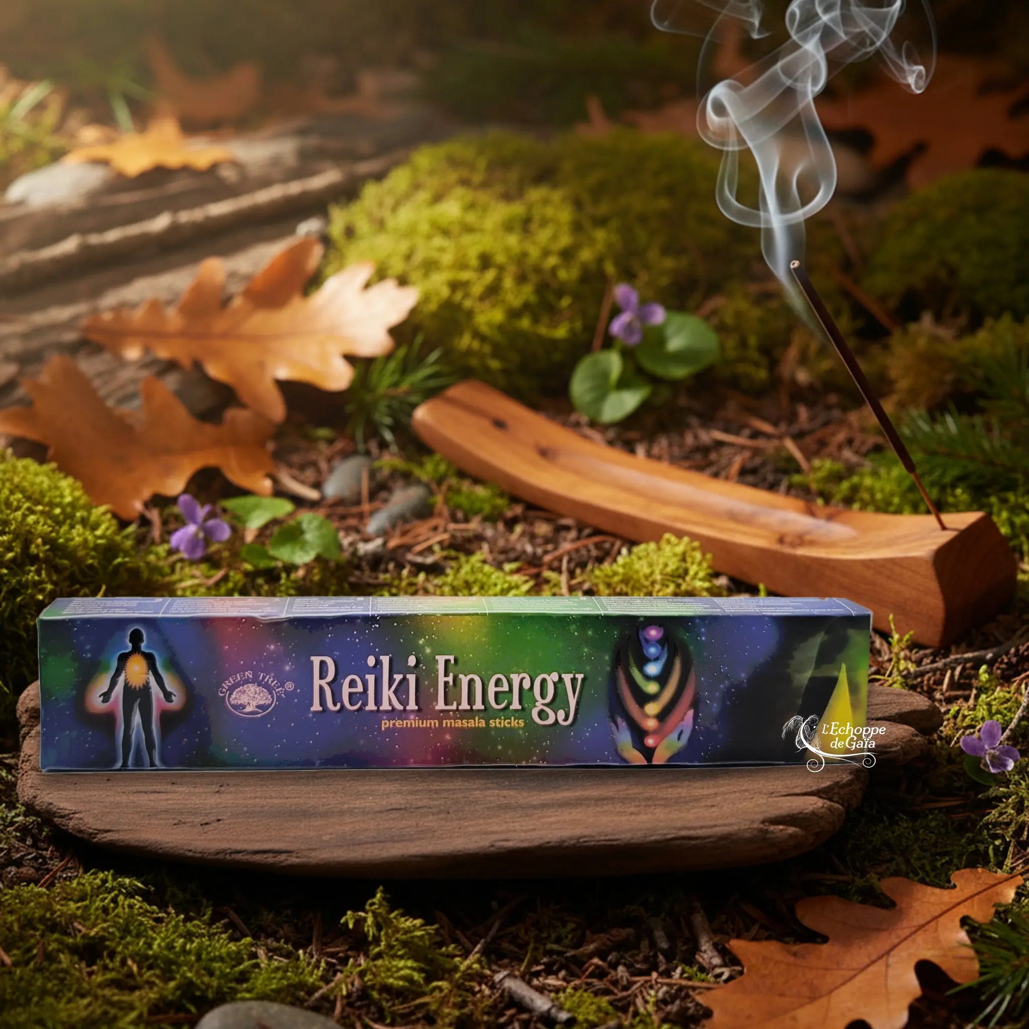 Boîte d’encens « Reiki Energy » Green Tree posée sur un lit de mousse en forêt, avec porte-encens en bois fumant à l’arrière-plan.