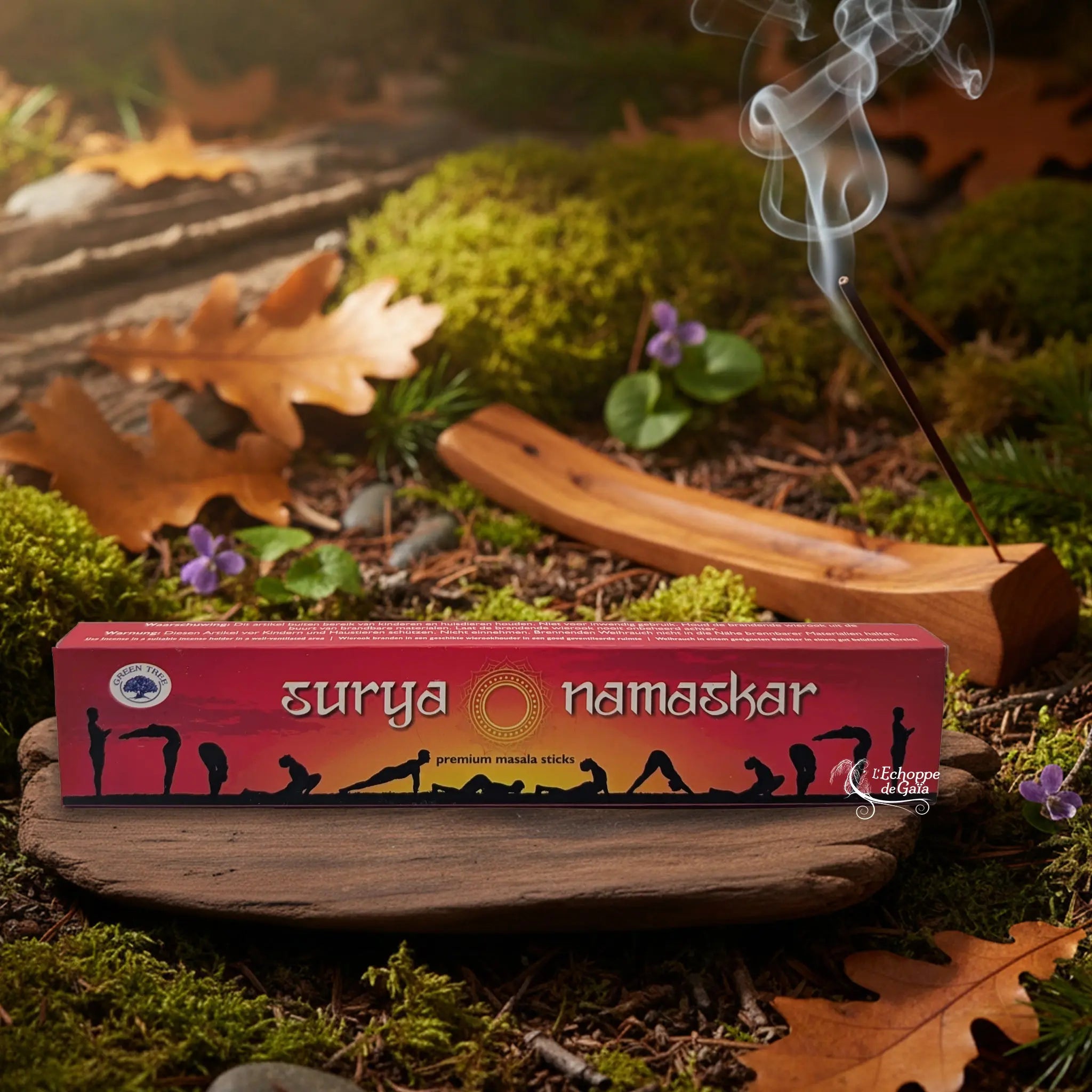 Boîte d’encens Green Tree “Surya Namaskar” posée sur un support en bois, décor de forêt automnale avec bâton d’encens fumant à l’arrière-plan.