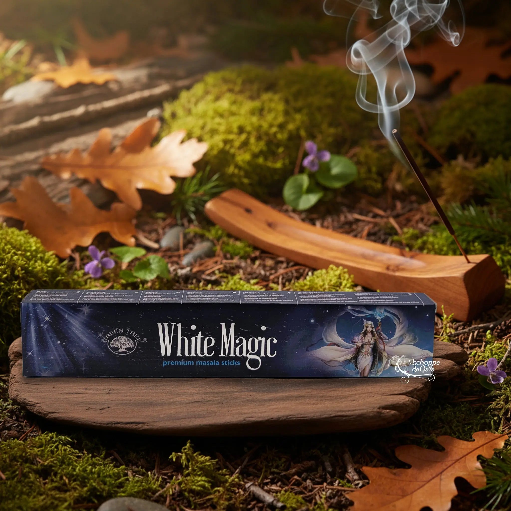 Boîte d’encens « White Magic » Green Tree posée sur un lit de mousse en forêt, avec porte-encens en bois fumant à l’arrière-plan.