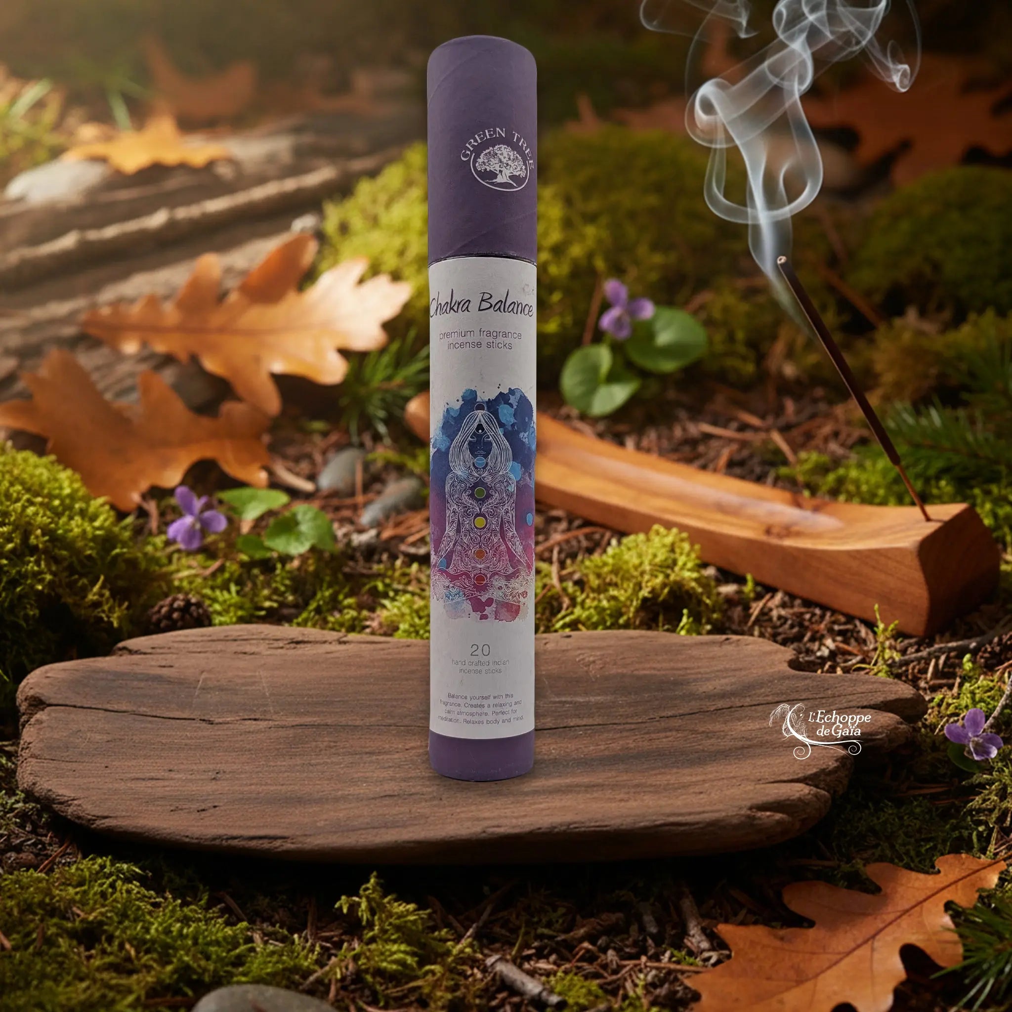 Tube d’encens Green Tree « Chakra Balance » sur une tranche de bois, avec un bâtonnet allumé dans un porte-encens en bois et de la fumée, décor nature.