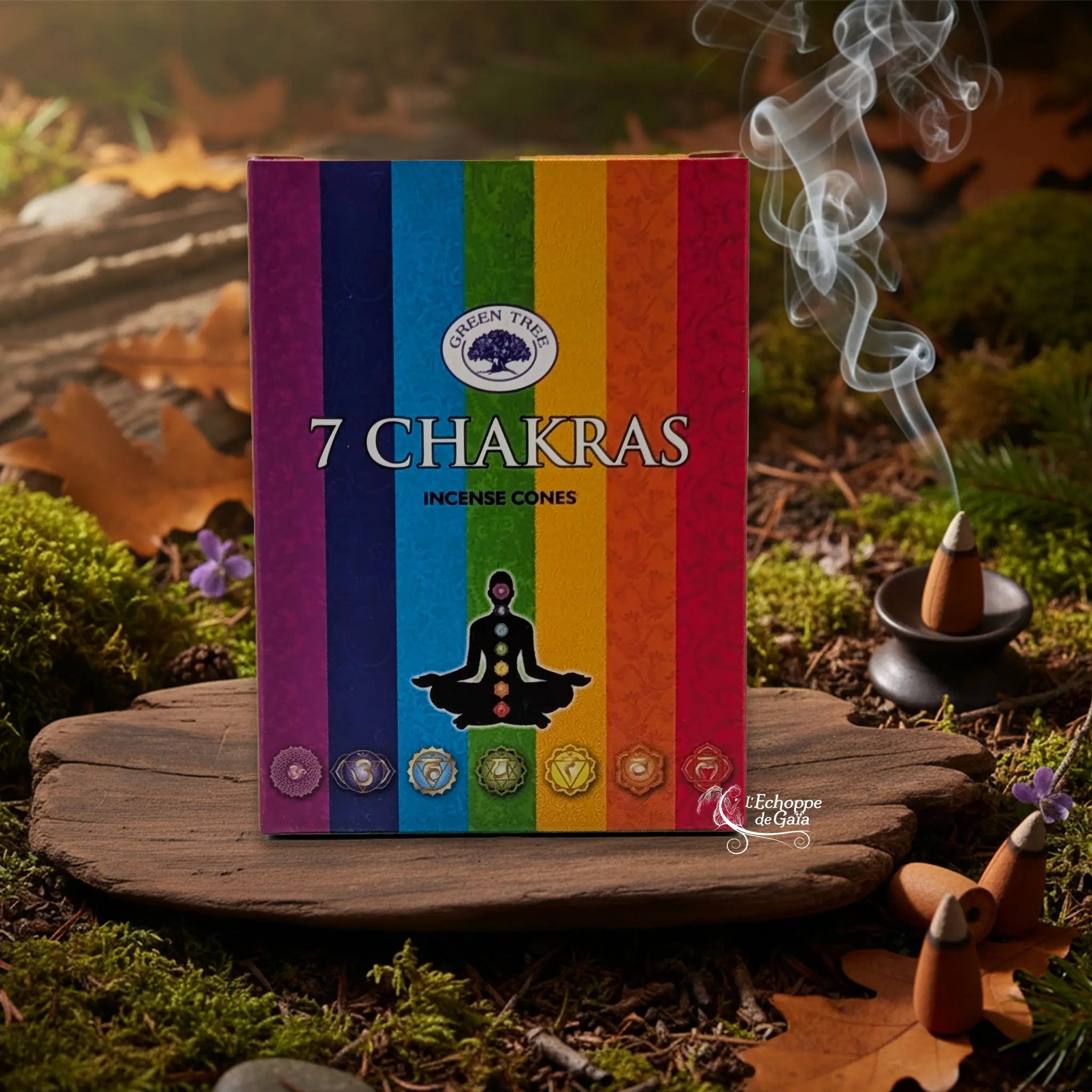 Boîte d’encens en cônes « 7 Chakras » Green Tree posée sur une planche de bois en décor de sous-bois, avec cône fumant sur porte-encens à droite.