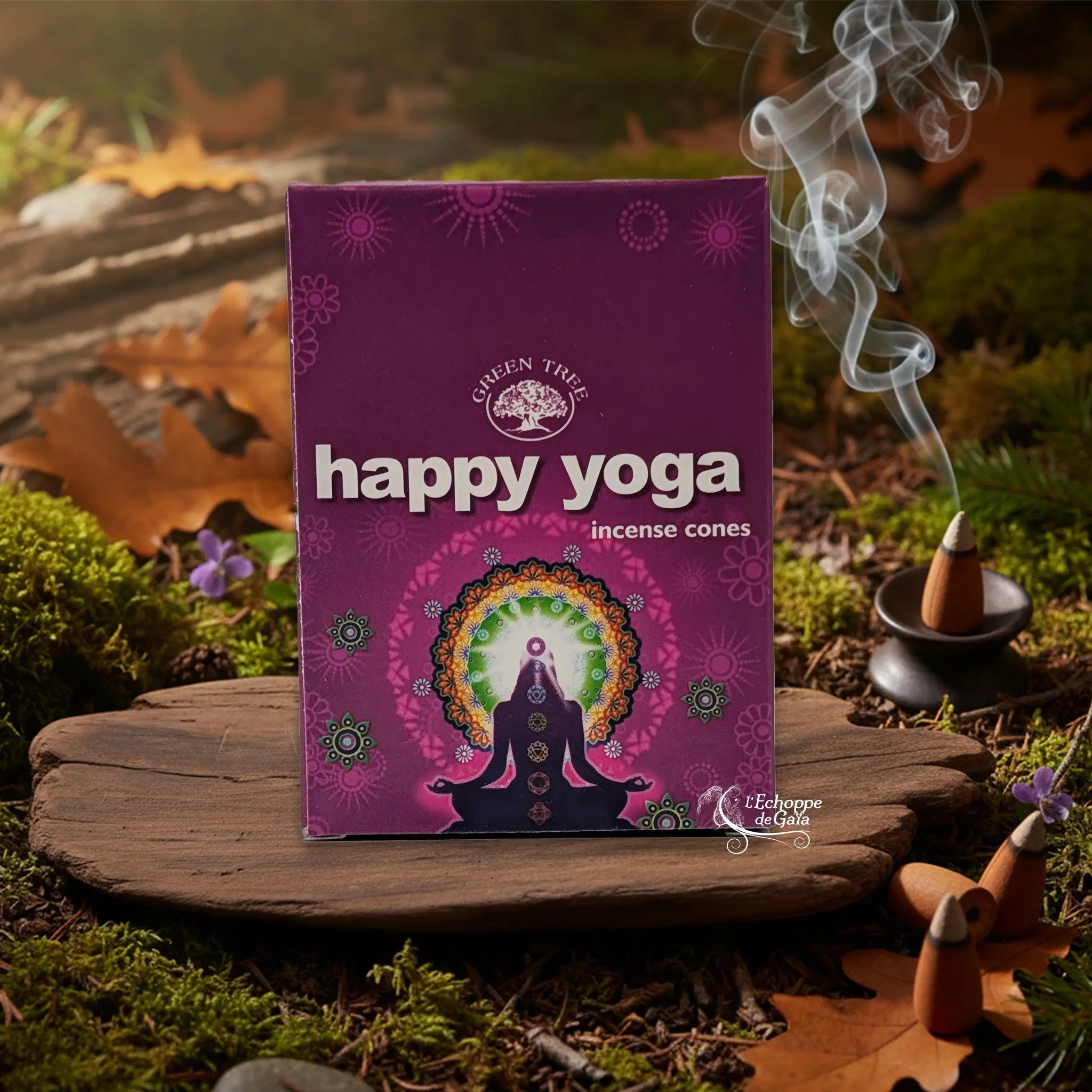 Boîte d’encens en cônes « Happy Yoga » Green Tree posée sur une planche de bois en décor de sous-bois, avec cône fumant sur porte-encens à droite.