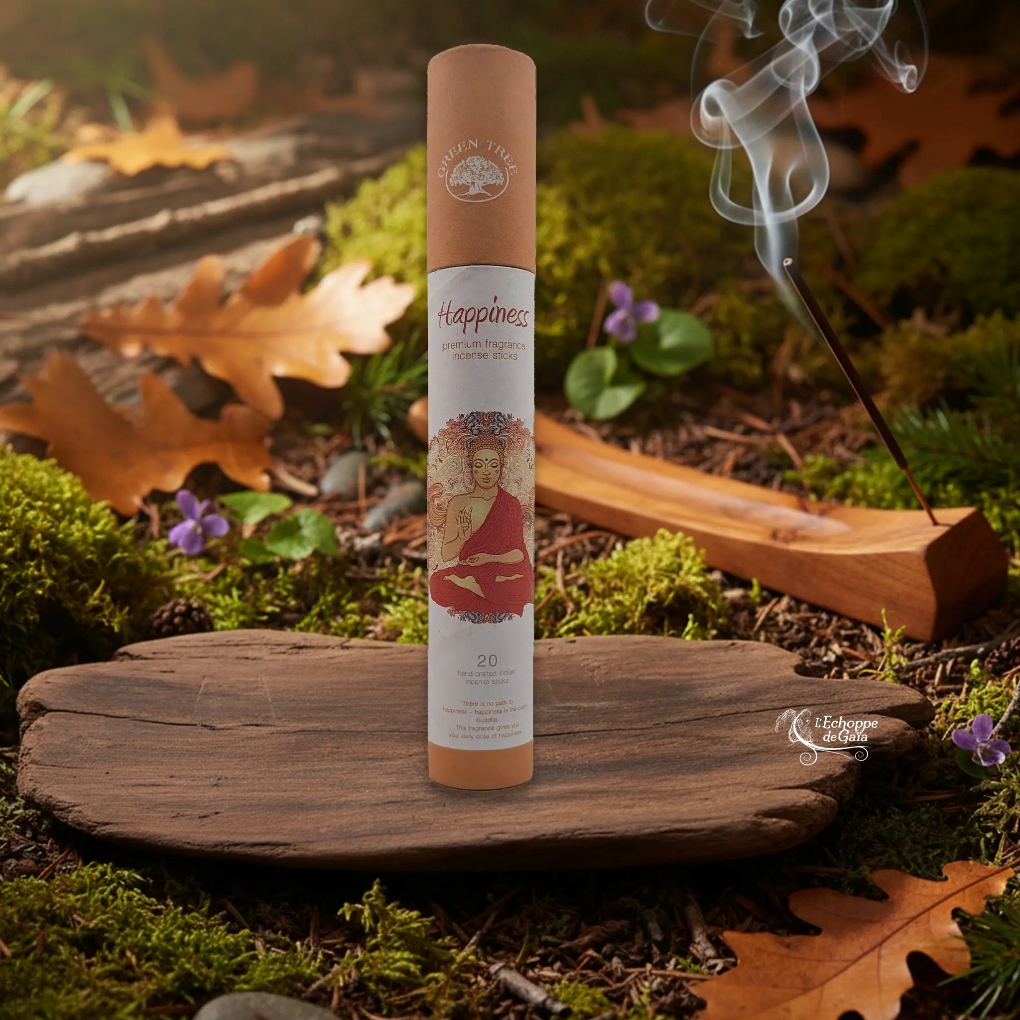 Tube d’encens Green Tree « Happiness » sur une tranche de bois, avec un bâtonnet allumé dans un porte-encens en bois et de la fumée, décor nature.