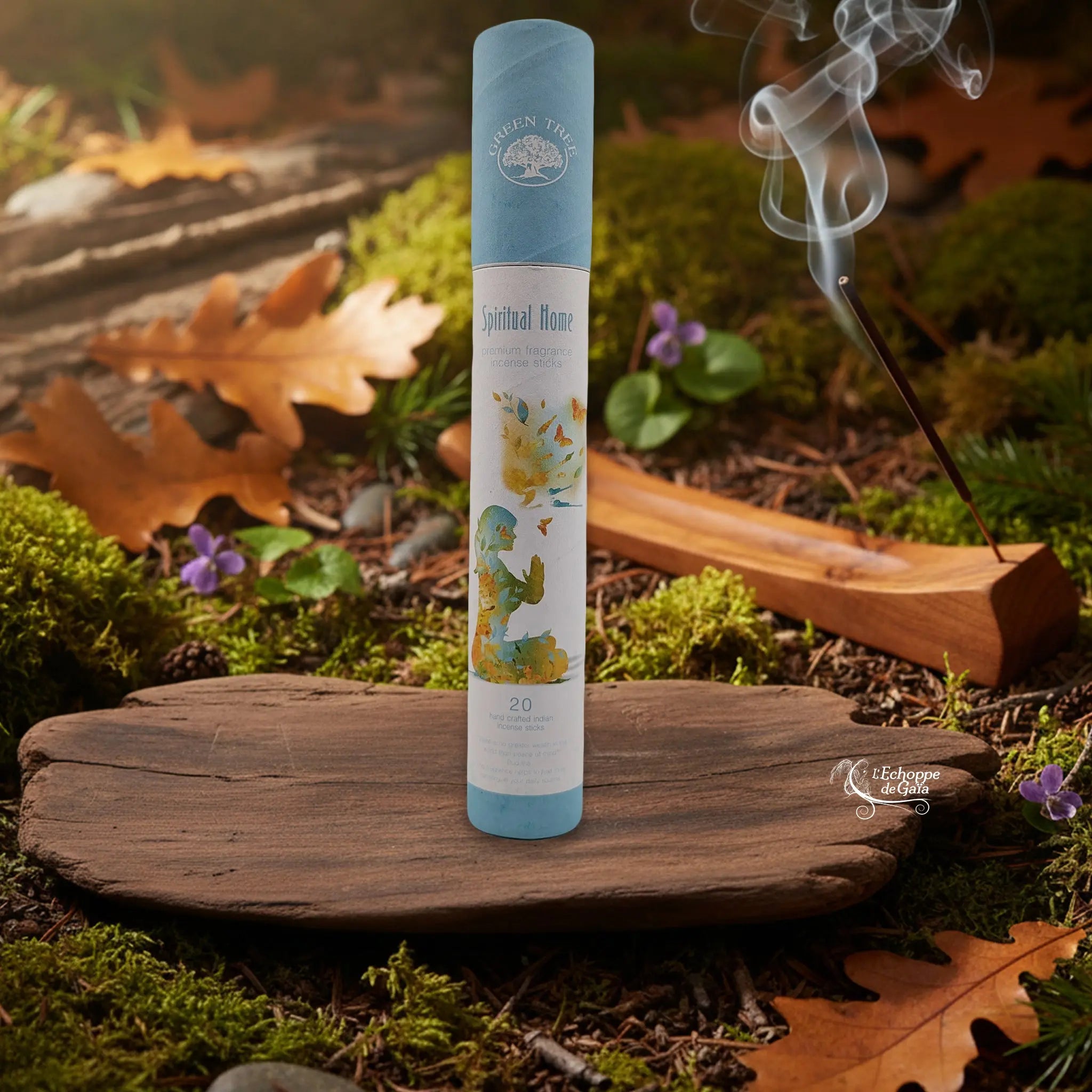 Tube d’encens Green Tree « Spiritual Home » sur une tranche de bois, avec un bâtonnet allumé dans un porte-encens en bois et de la fumée, décor nature.