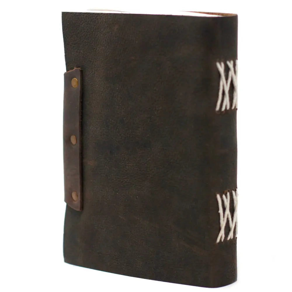 La vue arrière d'un carnet grimoire en cuir marron foncé, montrant une reliure artisanale à lacets blancs apparents sur le dos et une lanière de fermeture fixée par des rivets en laiton.