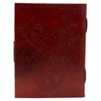 La couverture d'un carnet grimoire en cuir marron clair présentant un motif de deux dragons ailés face à face, finement embossé de manière symétrique avec des bordures ciselées.