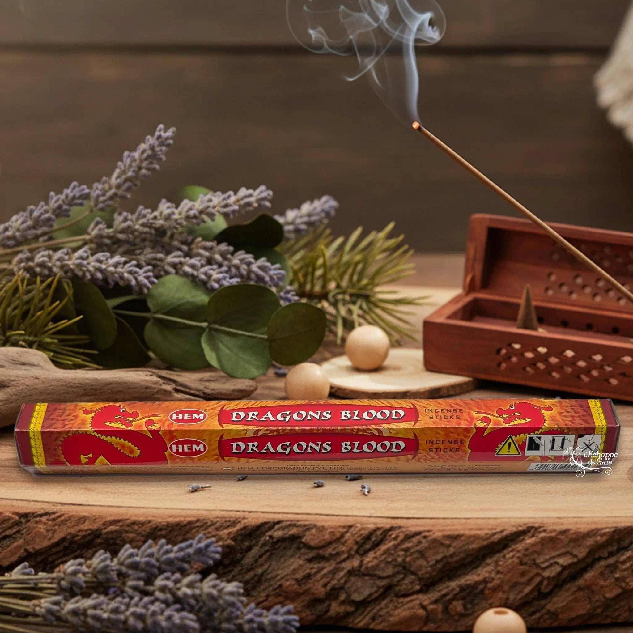 Boîte d'encens HEM "Dragons Blood" posée sur du bois avec de la lavande et un bâton d'encens fumant.