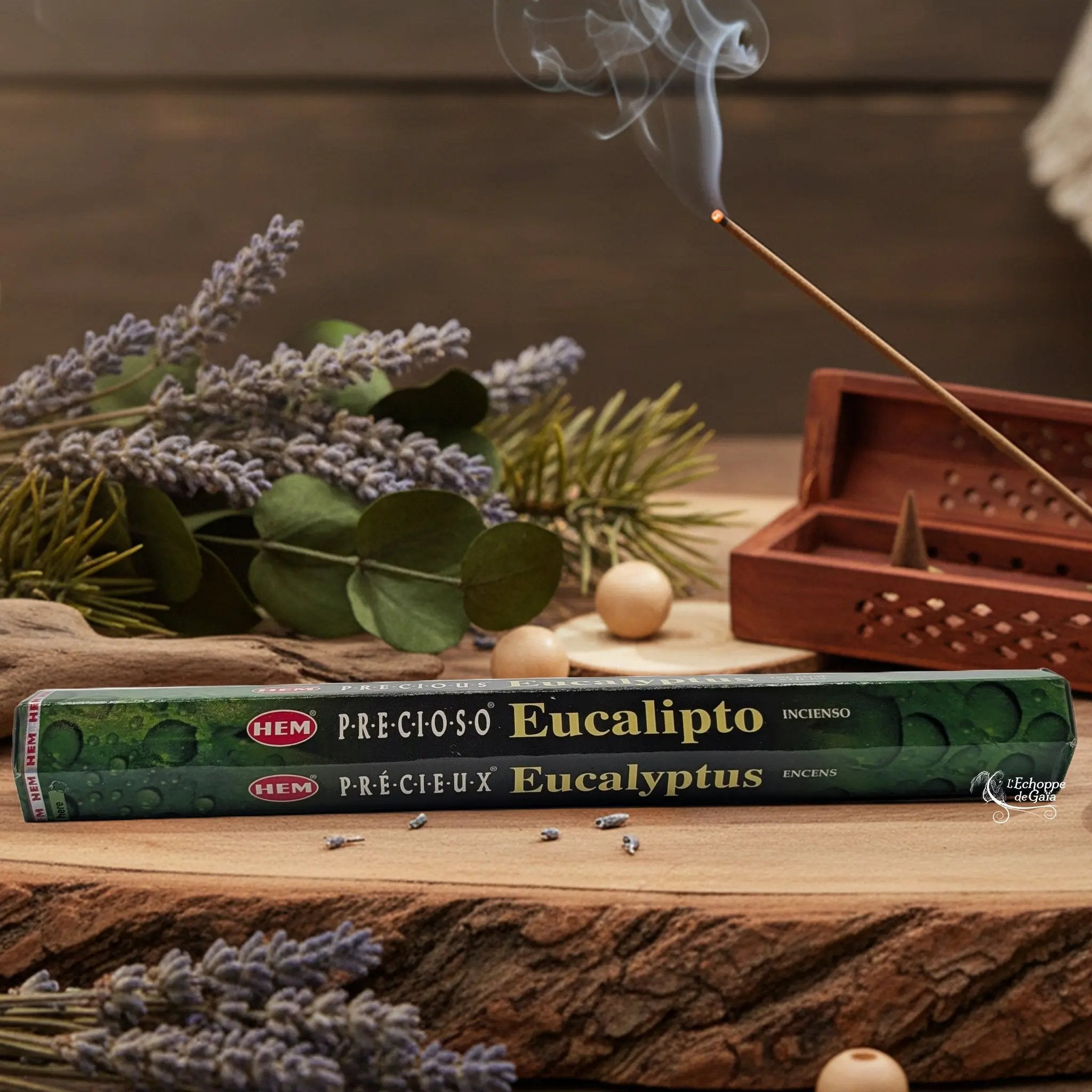 Boîte d'encens HEM "Precious Eucalyptus / Eucalipto" posée sur du bois avec de la lavande et un bâton d'encens fumant.