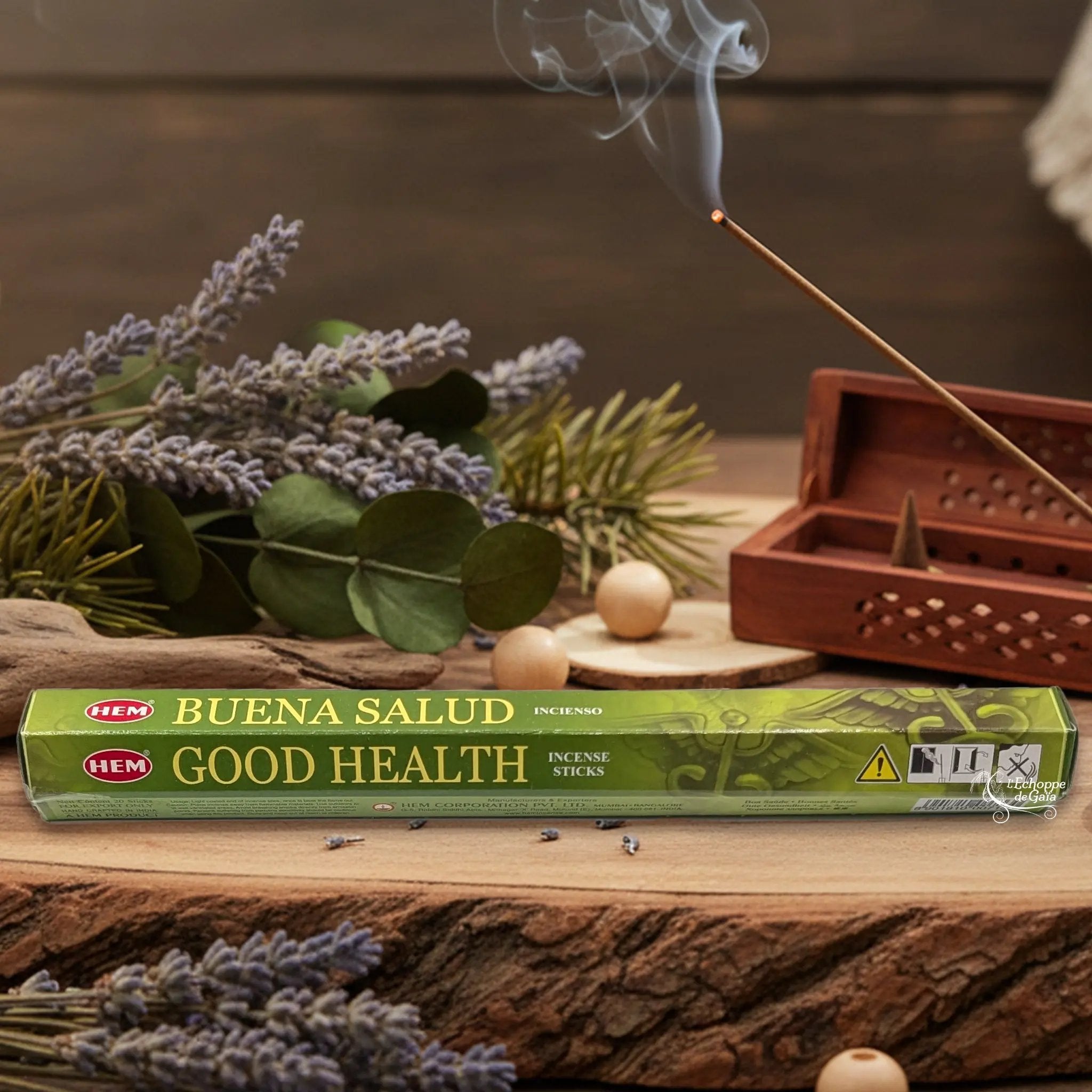 Boîte d'encens HEM "Good Health / Buena Salud" posée sur du bois avec de la lavande et un bâton d'encens fumant.