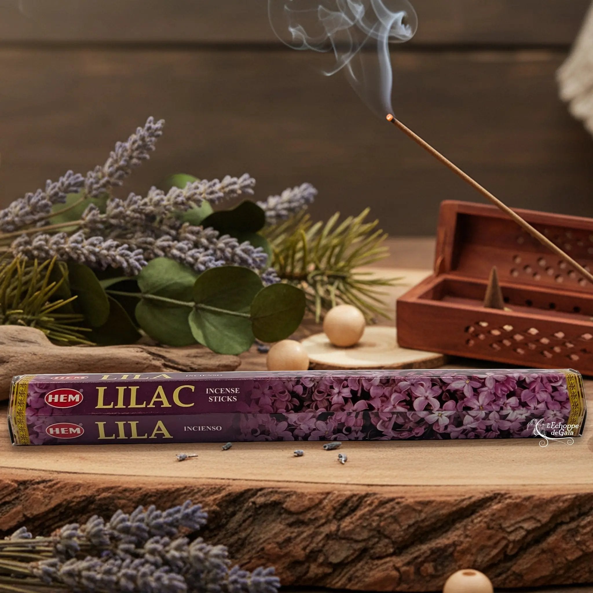 Boîte d'encens HEM "Lilac / Lila" posée sur du bois avec de la lavande et un bâton d'encens fumant.