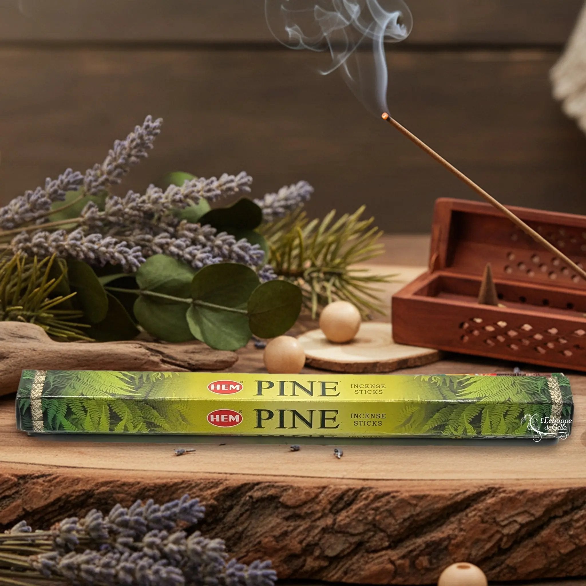 Boîte d'encens HEM "Pine" posée sur du bois avec de la lavande et un bâton d'encens fumant.