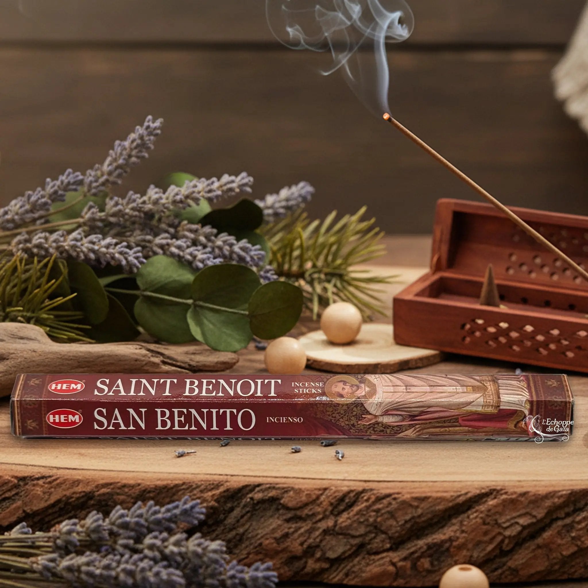 Boîte d'encens HEM "Saint Benoit / San Benito" posée sur du bois avec de la lavande et un bâton d'encens fumant.