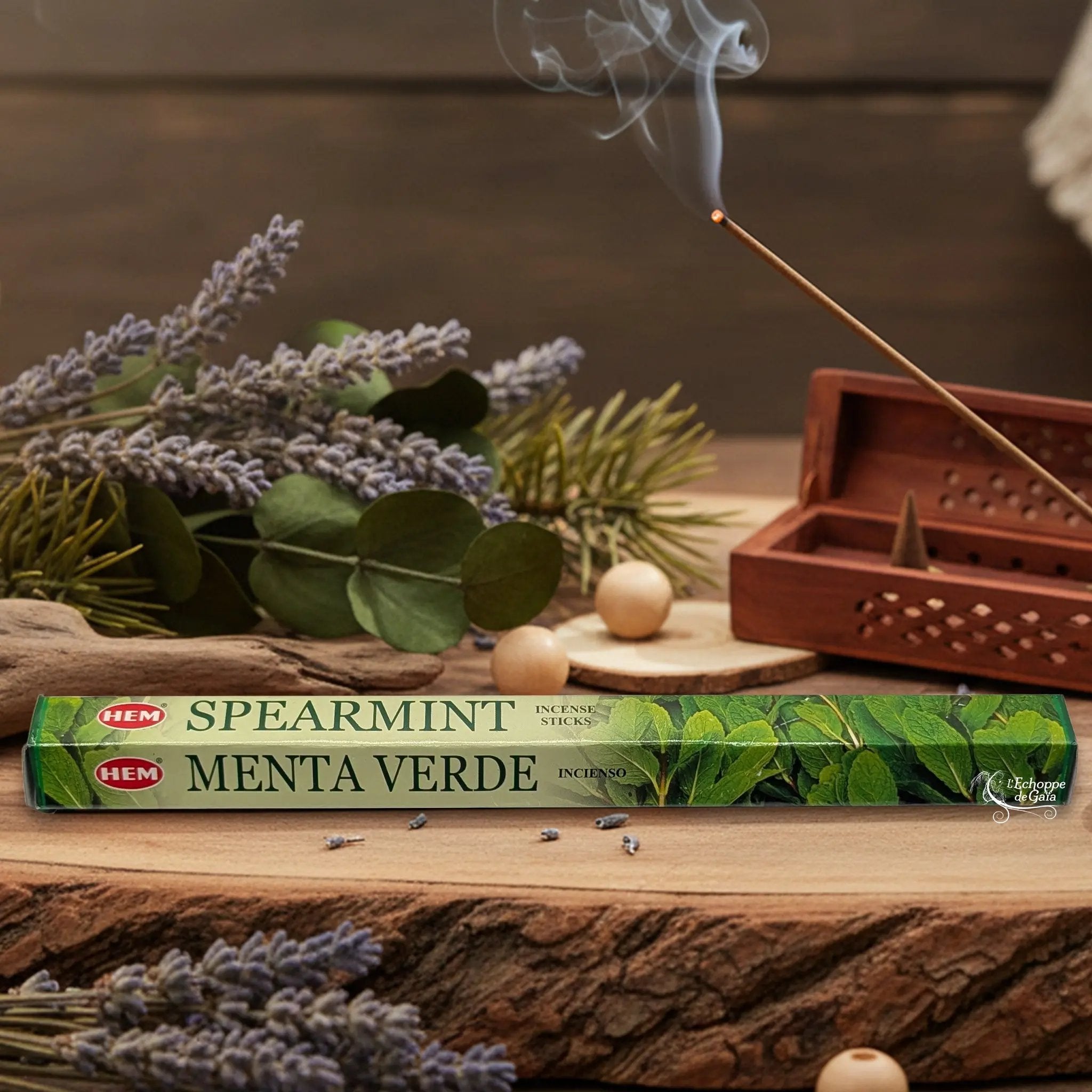 Boîte d'encens HEM "Spearmint / Menta Verde" posée sur du bois avec de la lavande et un bâton d'encens fumant.