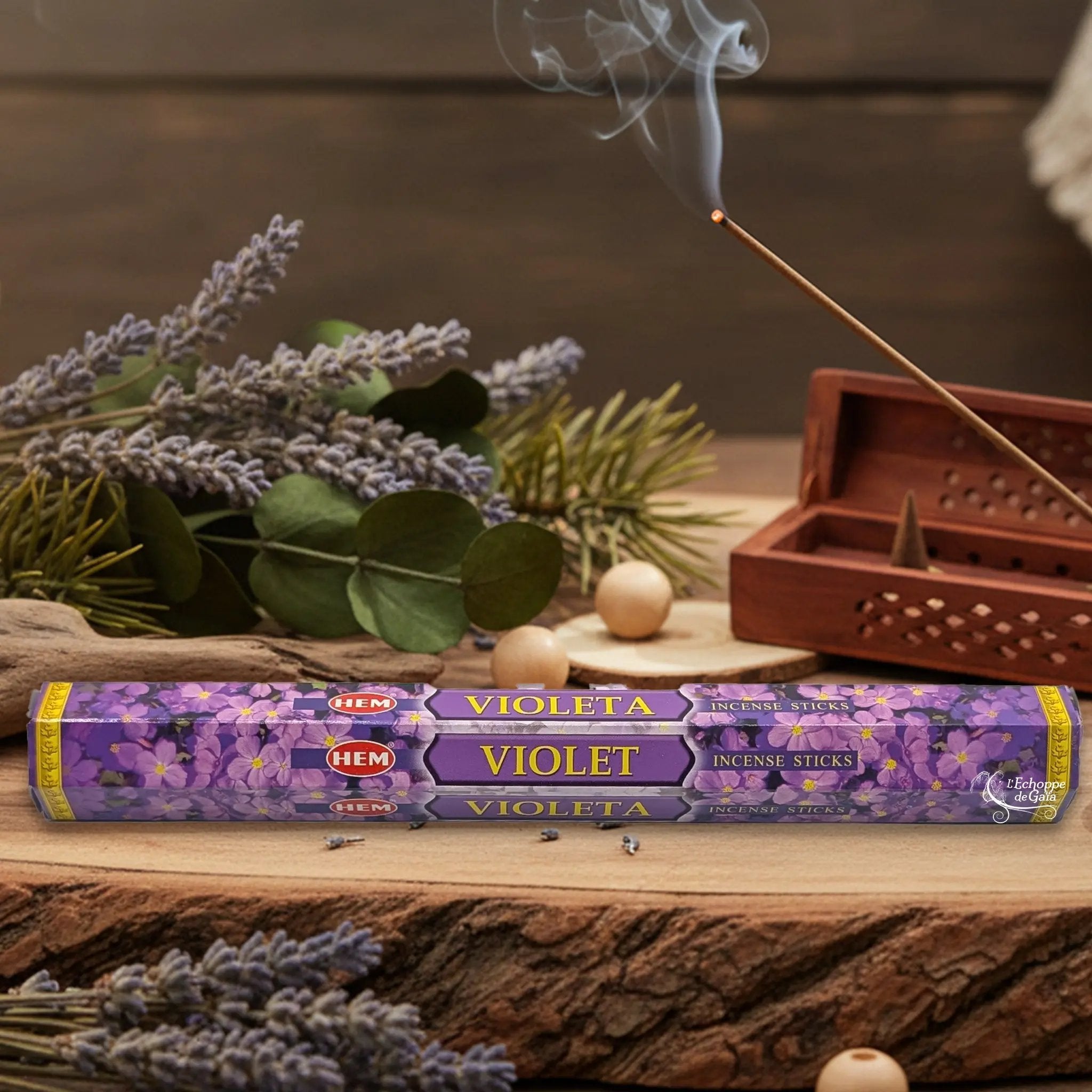 Boîte d'encens HEM "Violet / Violeta" posée sur du bois avec de la lavande et un bâton d'encens fumant.
