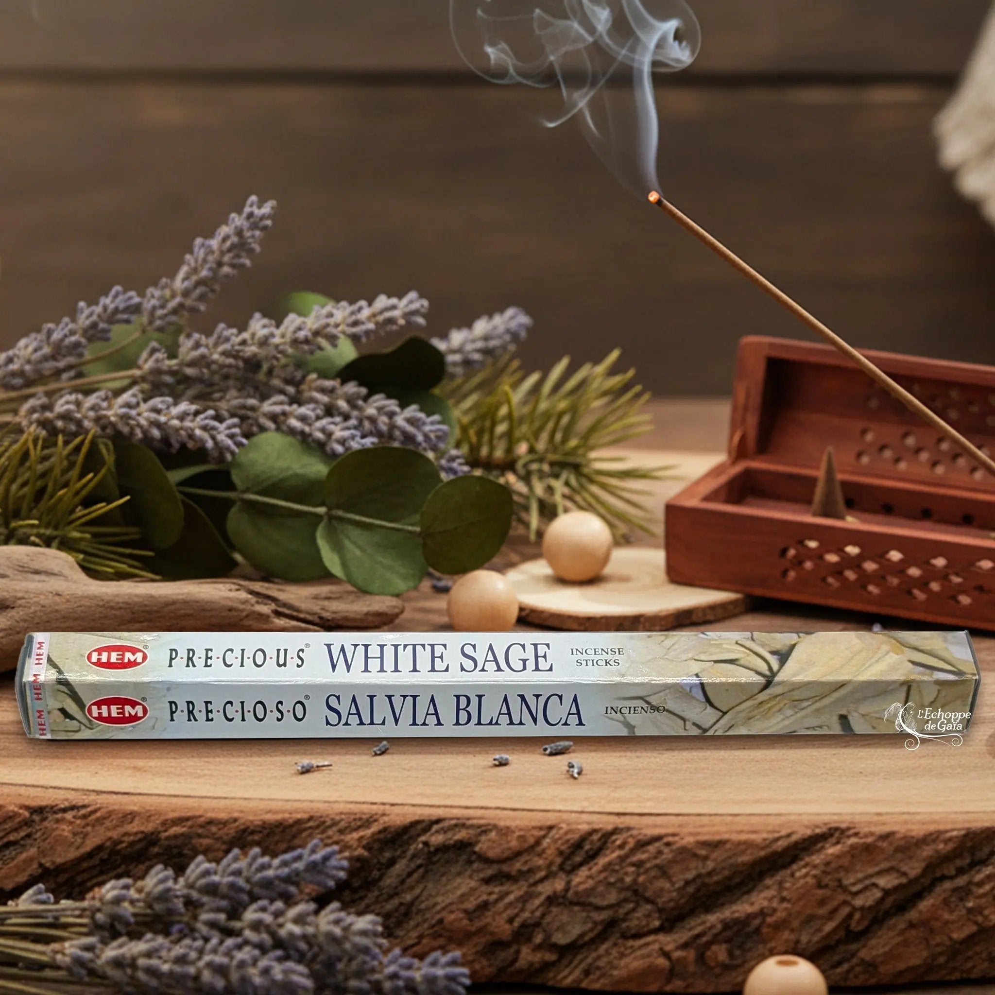 Boîte d'encens HEM "Precious White Sage / Salvia Blanca" posée sur du bois avec de la lavande et un bâton d'encens fumant.