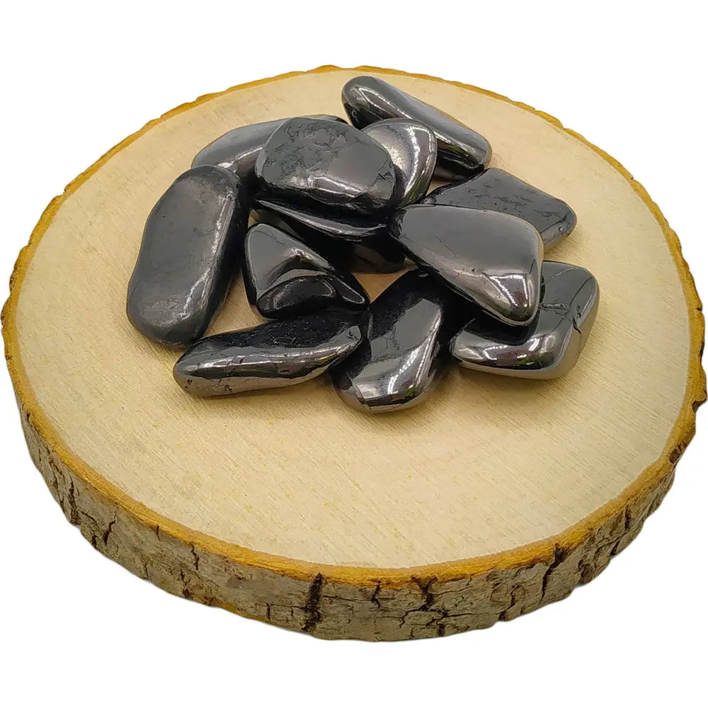 Pierres d'hématite polies, aux reflets métalliques gris foncé, disposées sur un support en bois circulaire.