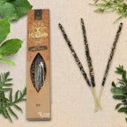 Boîte d'encens Herbio Copal naturel marron avec trois bâtonnets à tige jaune sur fond beige et feuilles vertes