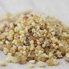 Gros plan sur un monticule de grains d'encens de résine Jasmin, montrant des billes translucides de couleur jaune clair, ambrée et brun foncé, sur une surface claire.