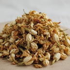 Gros plan sur un tas de fleurs de jasmin séchées, en petits boutons crème et dorés.