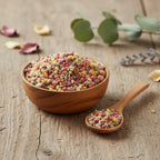 Grains d'encens de résine Jésus, mélange de couleurs (rouge, jaune, blanc/beige), dans un petit bol en bois clair avec cuillère, sur une planche de bois rustique.