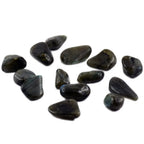 Un ensemble de pierres de labradorite roulées aux surfaces sombres et polies, parsemées de reflets irisés subtils, dispersées sur un fond blanc uni.