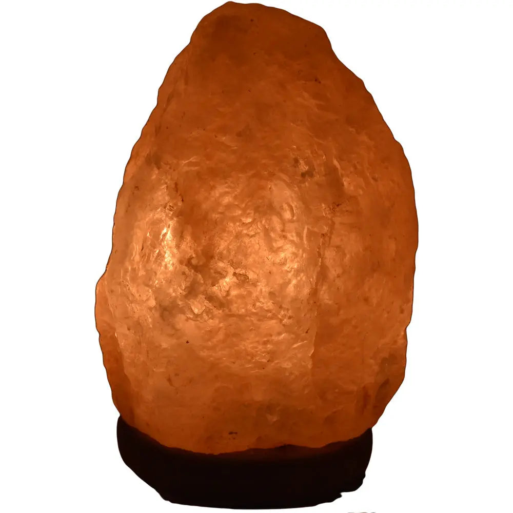 Lampe en sel de l'Himalaya de forme brute posée sur un socle noir, diffusant une lumière orangée.