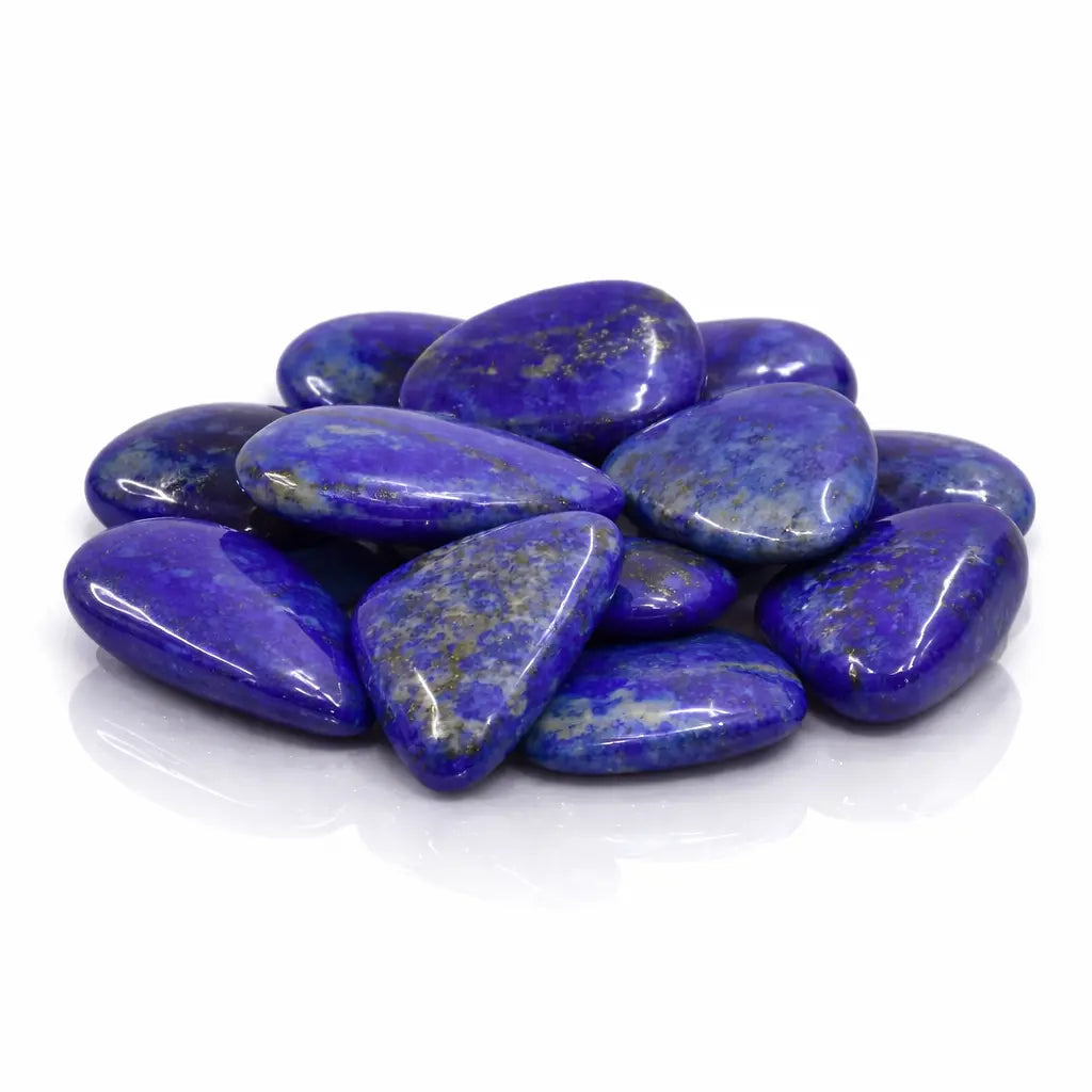 Un groupe de galets de lapis-lazuli d'un bleu outremer intense avec des inclusions dorées de pyrite, présenté sur un fond blanc pur avec des reflets brillants.