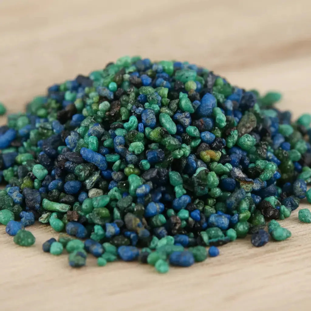 Gros plan sur un monticule de grains d'encens de résine Lavande, montrant un mélange dense de bleu électrique, de turquoise et de vert foncé, sur une surface en bois clair.