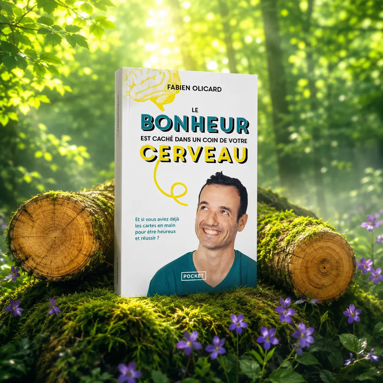 Livre Le Bonheur est Caché dans un Coin de votre Cerveau sur mousse sacrée au pied d'un arbre, entouré de fleurs violettes sous des rayons de soleil magiques.