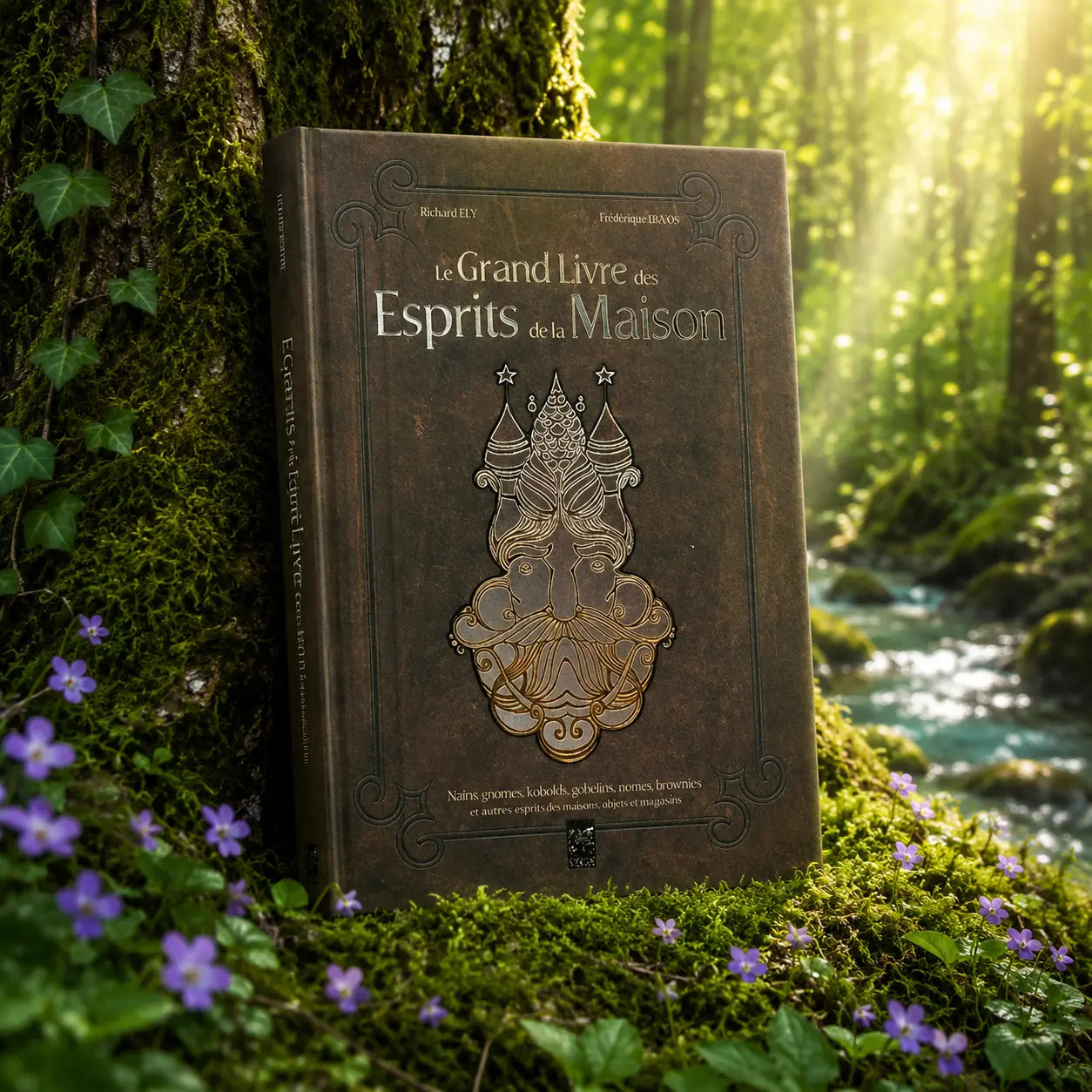 Livre Le Grand Livre des Esprits de la Maison sur mousse sacrée au pied d'un arbre, entouré de fleurs violettes sous des rayons de soleil magiques.