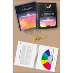 Présentation du coffret « Le Pendul'Or » de Dominique Coquelle, comprenant un livre de 33 planches à spirales ouvert sur un cadran de recherche de plan vibratoire, son étui de rangement, ainsi qu'un pendule émetteur-récepteur doré.