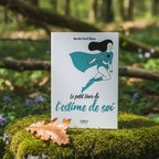 Livre blanc Le Petit Livre de l'Estime de Soi - Mariette Strub-Delain posé sur un rocher moussu, illustré d'une femme volant en super-héroïne.