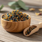 Encens de Lourdes en grains de résine ambrés et noirs dans une coupelle en bois avec petite cuillère sur table en bois.
