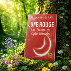 Livre Lune Rouge - Miranda Gray sur mousse sacrée au pied d'un arbre, entouré de fleurs violettes sous des rayons de soleil magiques.
